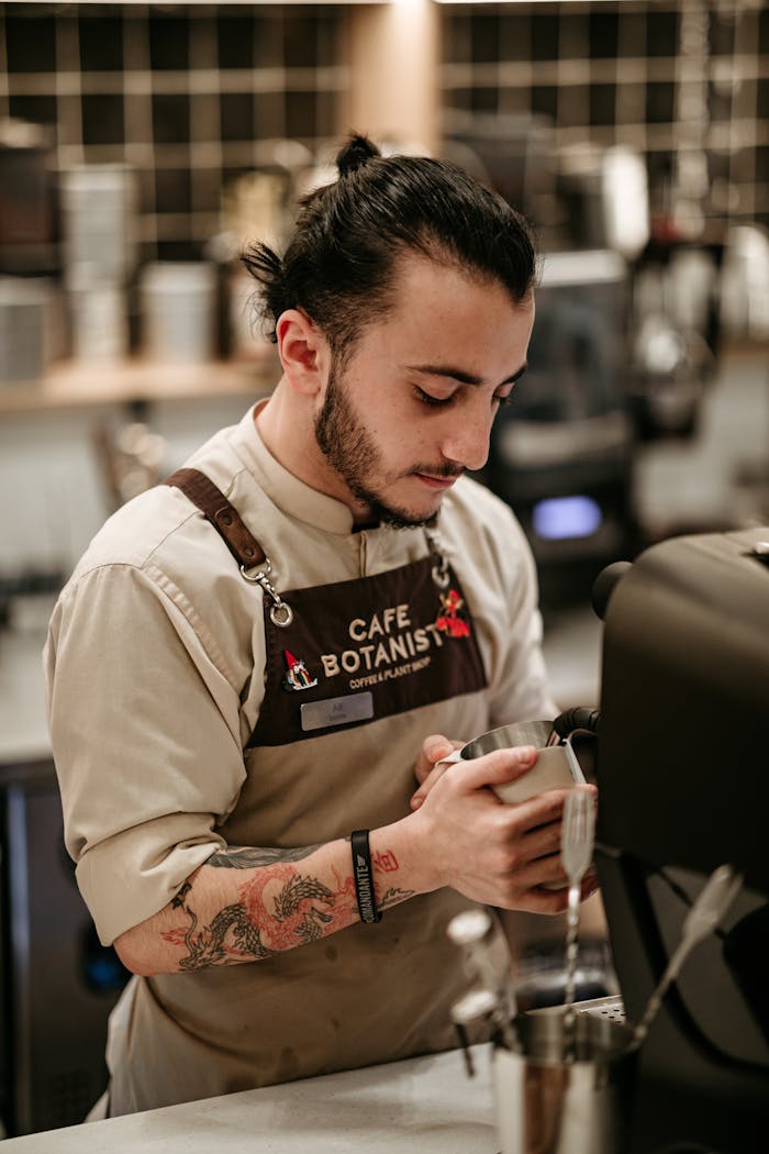 services-01 Barista preparing coffee with skill and focus at a trendy café location.